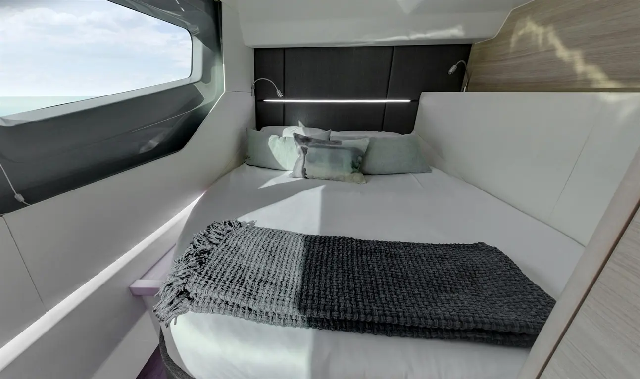 Modern bedroom with a double bed, decorative cushions, a grey throw, and a large window offering scenic views.
